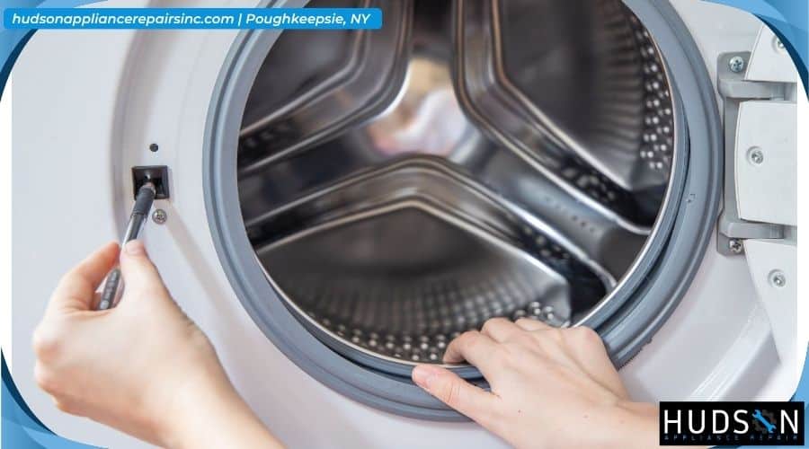 Technician inspecting a torn rubber door bellows on a front-load washing machine