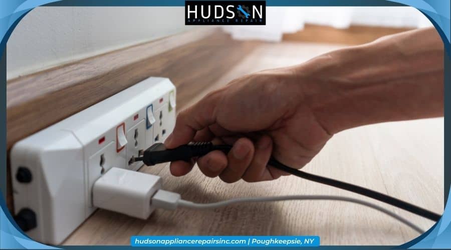 disconnect-garbage-disposal-power - Hands safely unplugging an appliance power cord from a wall outlet.