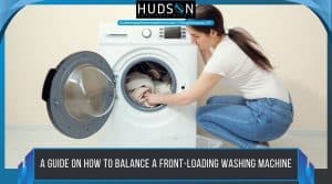 how-to-balance-a-front-loading-washing-machine - A woman kneeling to adjust clothes inside a front-loading washing machine, with text that reads, "A guide on how to balance a front-loading washing machine."